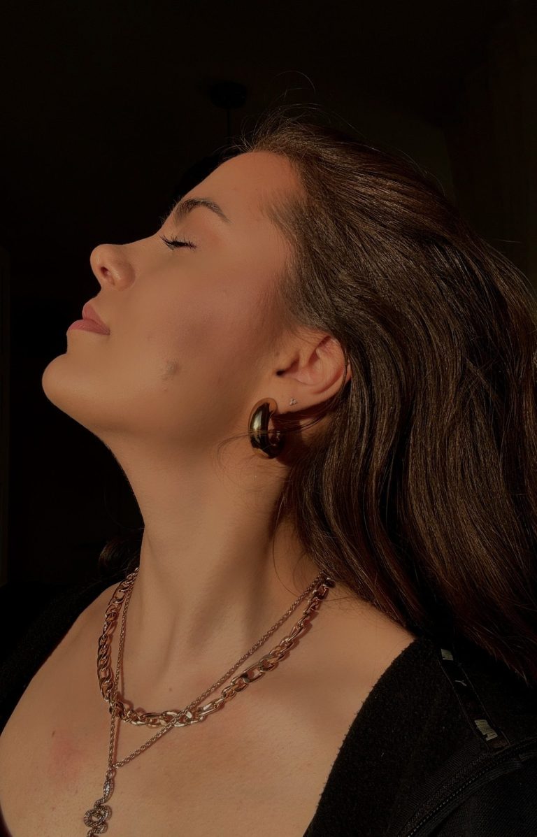 LIIVIA neigt den Kopf leicht nach oben, in sanftem Licht.